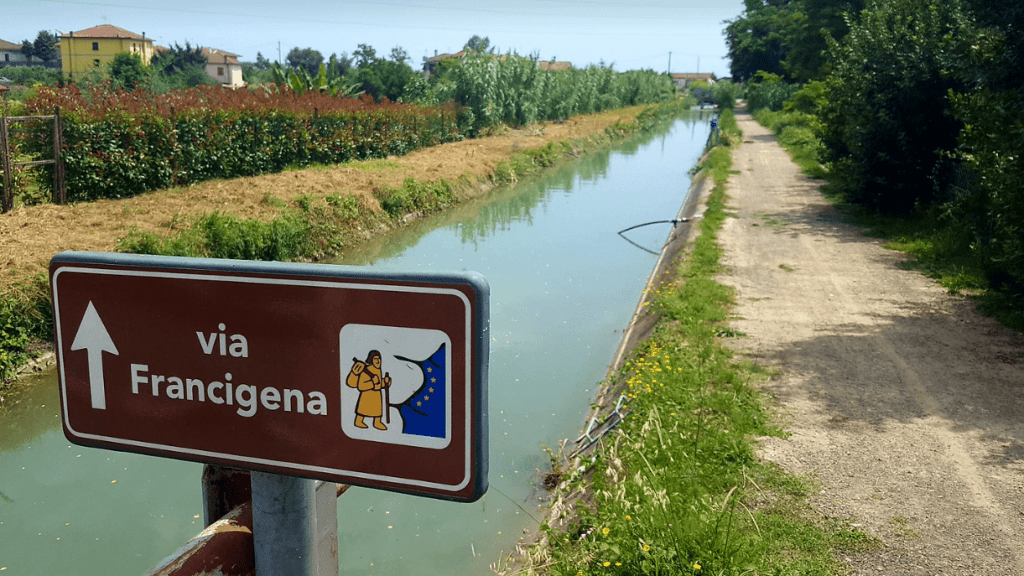 Tappa Via Francigena Aulla - Avenza. Segnale della via francigena con canale d'acqua come sfondo